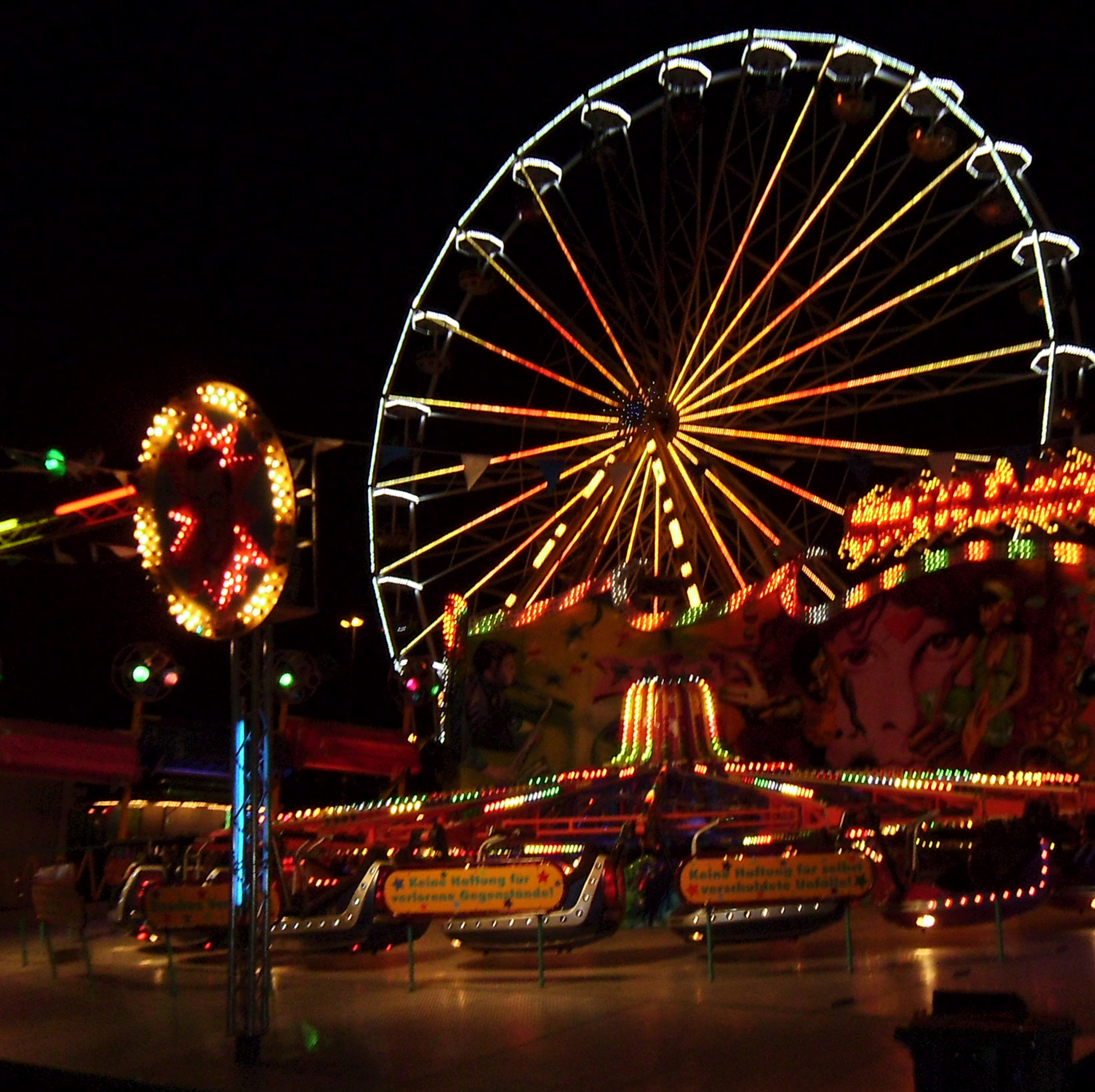 Beleuchtetes Riesenrad und Karussells  abends während der Saarbruecker Kirmes