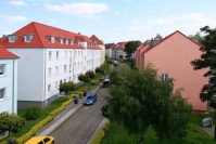 Straße mit Kopfsteinpflaster aus Dachwohnung gesehen. Lins Häuser hellblau, rechts Häuser orange, Bäume. Straße mit Kopfsteinpflaster aus Dachwohnung gesehen. Lins Häuser hellblau, rechts Häuser orange, Bäume.