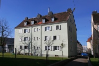 Altbau mit Spitzdach, 4 Etagen, hellgrüne Fassade. Vorne Grünfläche, Wäschestangen. Im Hintergrund Straße. Altbau mit Spitzdach, 4 Etagen, hellgrüne Fassade. Vorne Grünfläche, Wäschestangen. Im Hintergrund Straße.