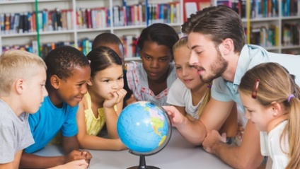 Schüler erkunden mit ihrem Lehrer die Weltkugel 
