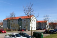 Drei sanierte Mehrfamilienhäuser mit jeweils 3 Etagen und Satteldach. Dazwischen Grünflächen mit Bäumen. Vorne Anliegerstraße mit Parkplätzen quer zur Straße. Drei sanierte Mehrfamilienhäuser mit jeweils 3 Etagen und Satteldach. Dazwischen Grünflächen mit Bäumen. Vorne Anliegerstraße mit Parkplätzen quer zur Straße.