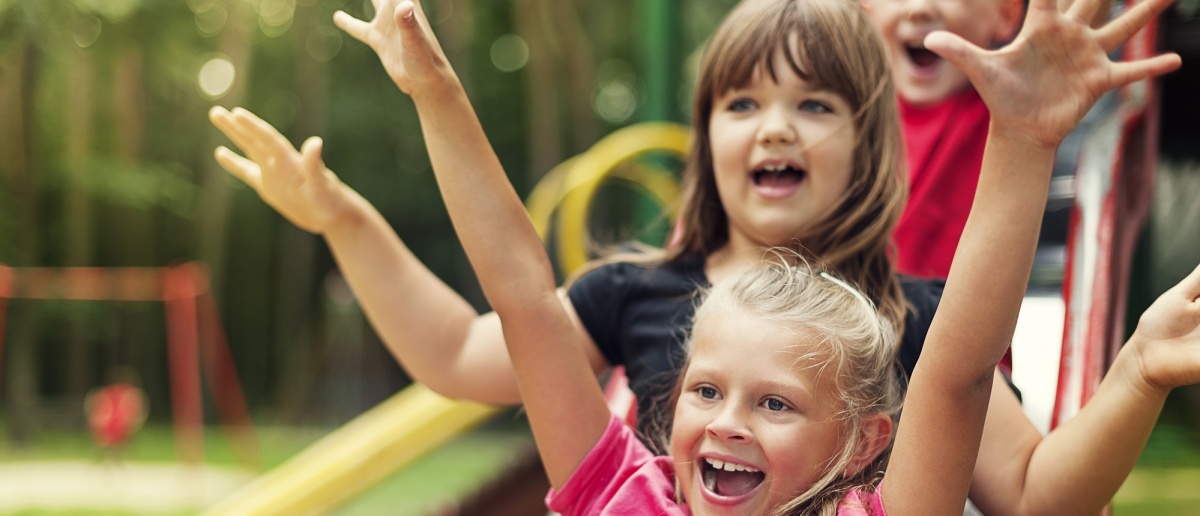 Kinder rutschen auf einem Spielplatz