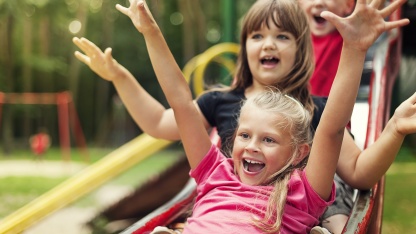 Kinder rutschen auf einem Spielplatz (Foto: gpointstudio/shutterstock)