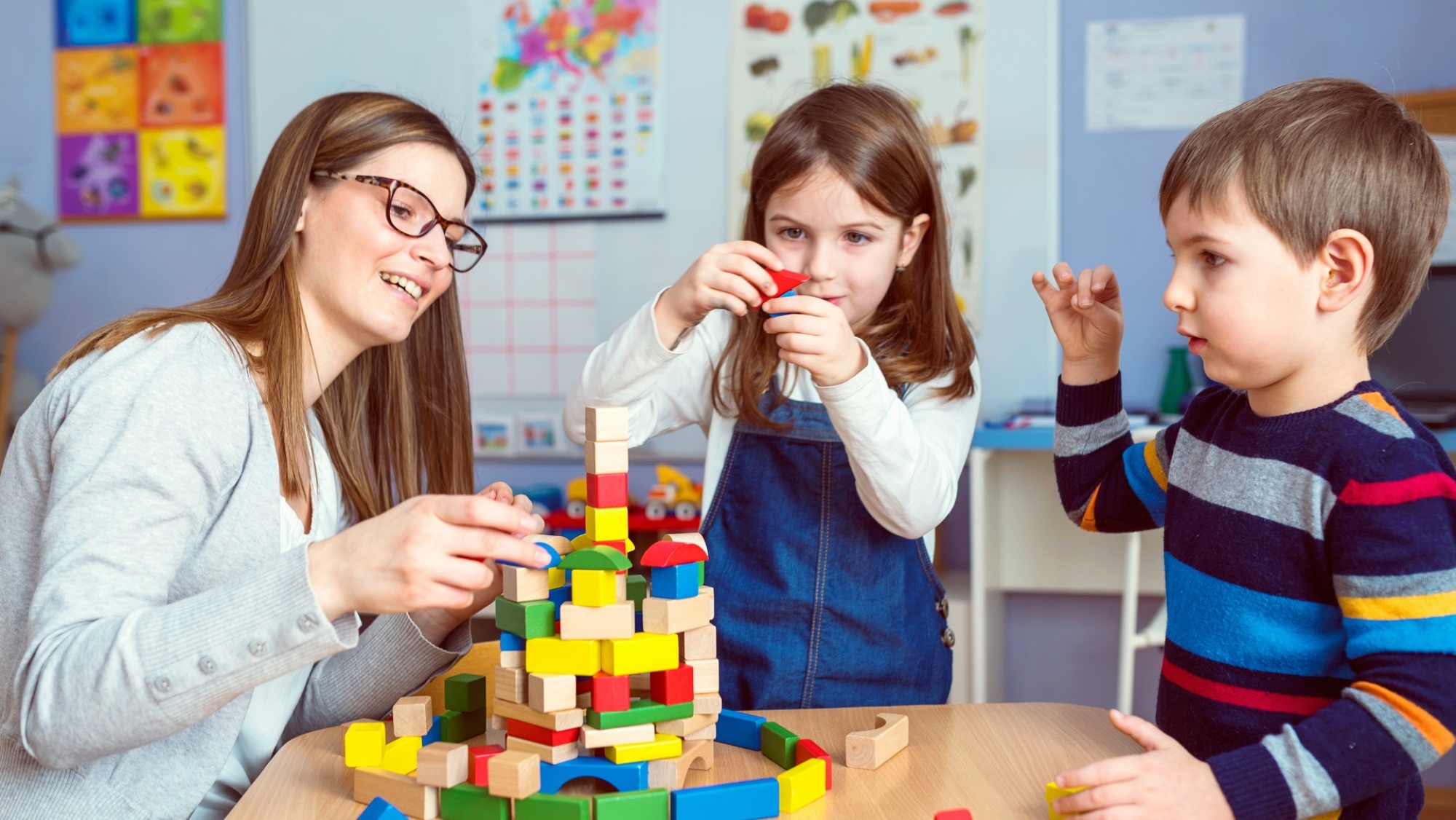Kinder und Erzieherin spielen mit Bauklötzen (Foto: Lordn/shutterstock)
