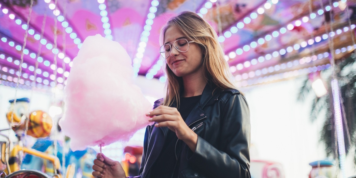 Junge Frau isst Zuckerwatte auf einem Jahrmarkt 