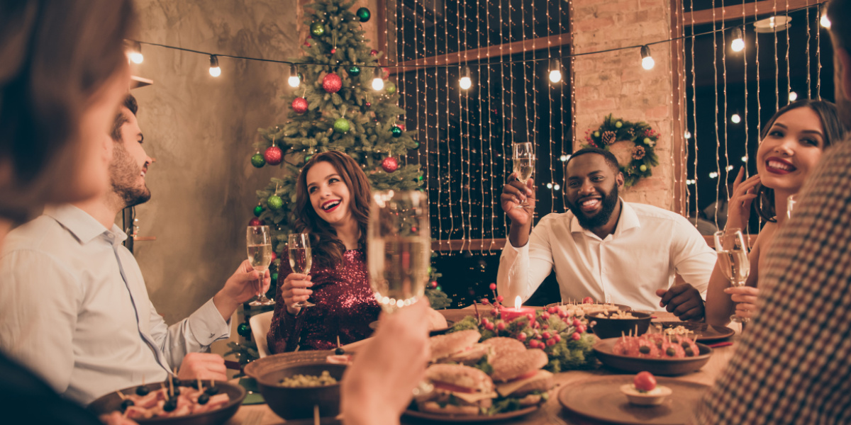 Mehrere Menschen an weihnachtlich gedecktem Tisch beim Essen