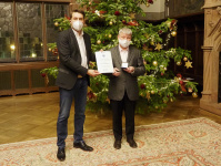 OB Conradt und Heinz Peter Engels mit Urkunde und Bürgermedaille vor Weihnachtsbaum im Rathausfestsaal (v.l.)