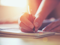 Hand mit Stift und Buch