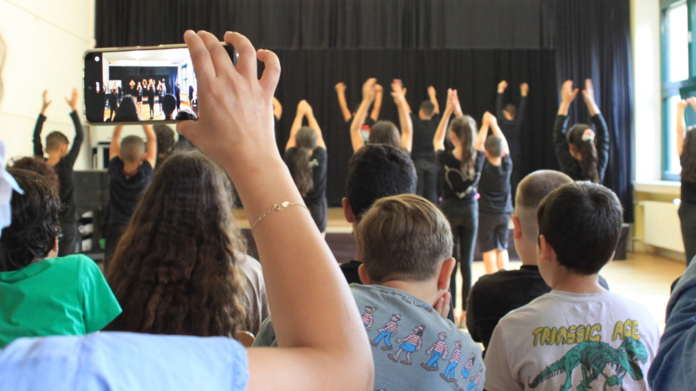 Kinder im Publikum blicken auf Kinder auf der Bühne, die eine Tanztheatervorstellung machen