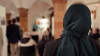 Rückansicht Frau mit Kopftuch, blick in den Saal verschwommen