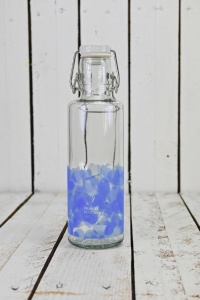 Glasflasche mit blauen Herzen vor hölzernem Hintergrund 