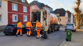 Drei Müllmänner an einem Müllwagen in Saarbrücken