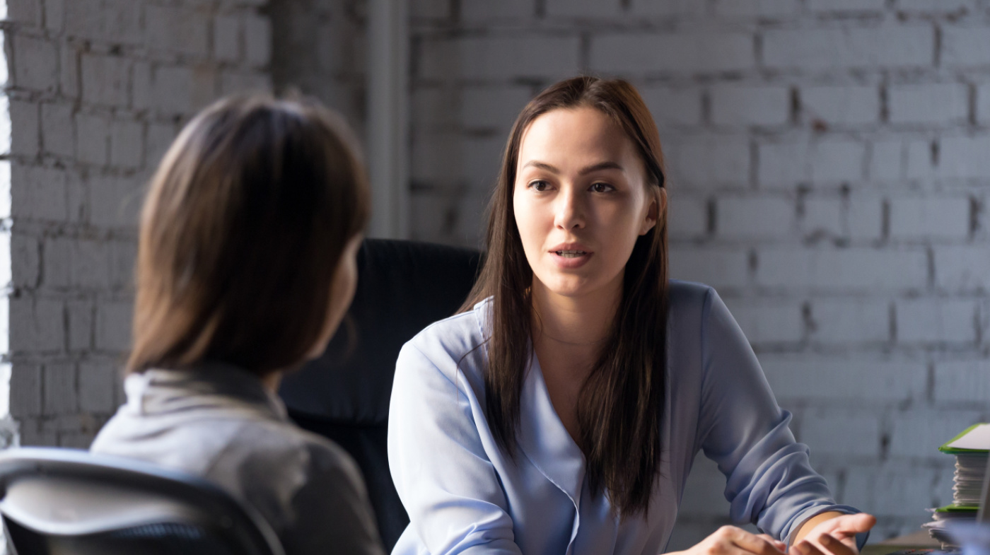 Dame berät Person - sitzend an einem Tisch