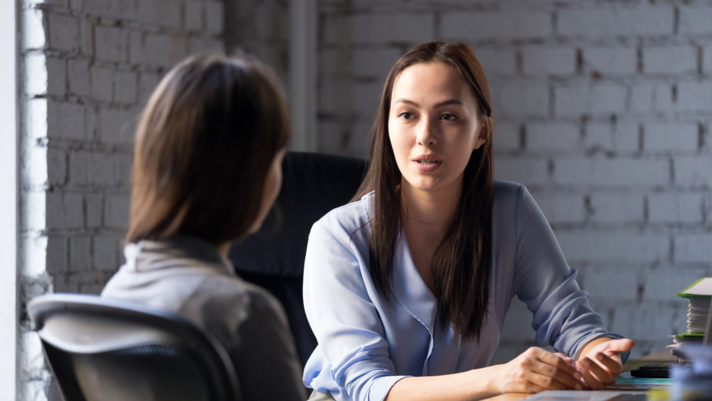 Dame berät Person - sitzend an einem Tisch
