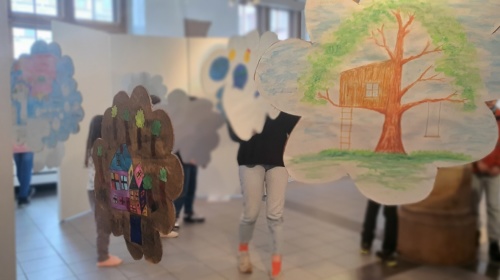 bunt gestaltete Wolken aus Pappe hängen verteilt im Saal