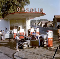 Ein VW Käfer an einer Tankstelle im Jahr 1957. Weibliche Tankwarte, wie hier zu sehen, waren jedoch recht selten. 