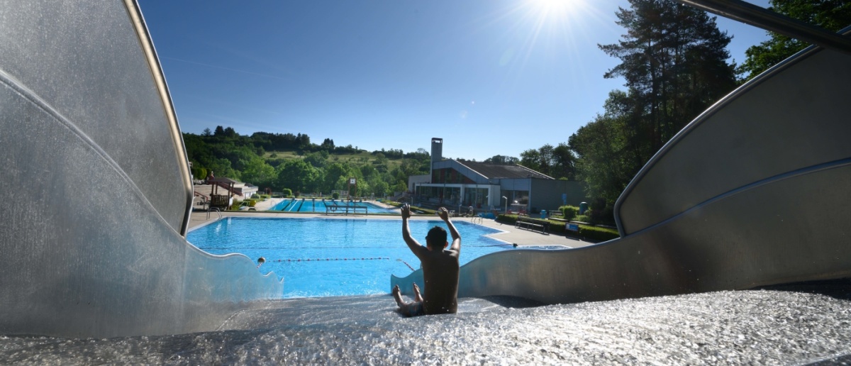 Eine Person sitzt auf einer Rutsche, davor ein Schwimmbecken