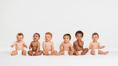 Babys sitzen vor einer weißen Wand.