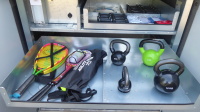 Sportbox Schublade mit vier Gewichten von vier bis 16 Kilo, daneben Schläger.