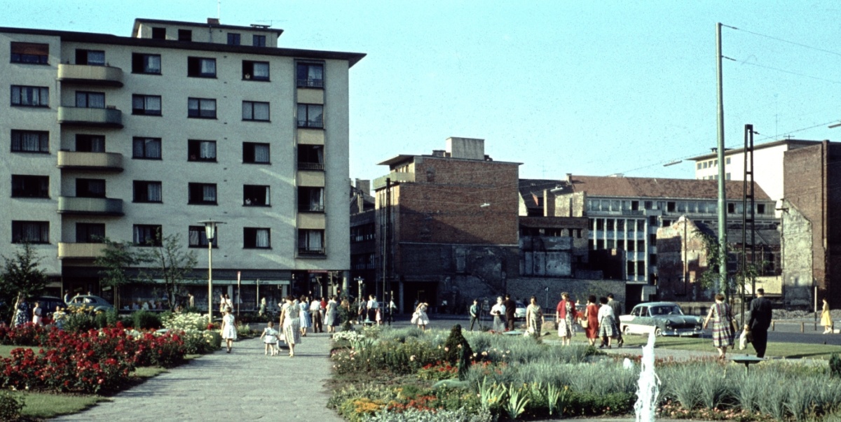 Foto von der Eisenbahnstraße aus den 60er/70 Jahren, im Vordergrund ein Park mit Brunnen, im Hintergrund ein Mehrfamilienhaus. 