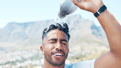 Mann schüttet sich eine Flasche Wasser über den Kopf - Tipps gegen Hitze