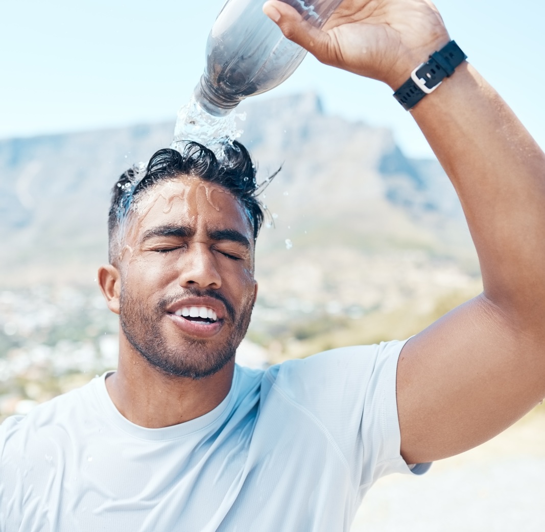 Mann schüttet sich eine Flasche Wasser über den Kopf - Tipps gegen Hitze