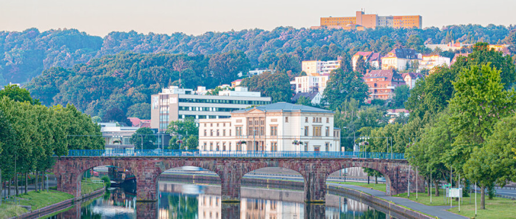 Ansicht über Fluss auf alte Brücke mit großen Gebäuden im Hintergrund