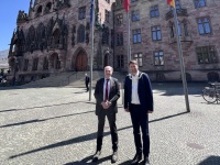 Antrittsbesuch des französischen Generalkonsuls Jérôme Spinoza Zwei Personen in Anzügen stehen vor einem Fahnenmast, im Hintergrund befindt sich das Rathaus St. Johann