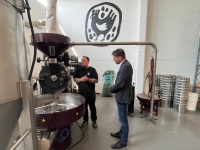 Zwei Männer stehen in einer Halle neben einem industriellen Kaffee-Röster