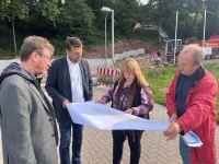 Vier Personen schauen auf einen Bauplan, im Hintergrund finden Bauarbeiten statt