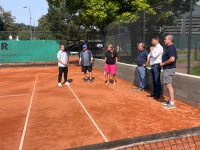 Eine Gruppe Menschen steht auf einem Tennisplatz