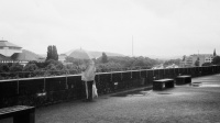 Schwarz-weiß Fotografie des Blickes vom Saarbrücker Schloss auf die Franz-Josef-Röder-Straße an einem Regentag mit Mann mit Regenschirm