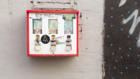 Kaugummiautomat vor zwei Wänden in grau und schwarz mit blauen Punkten