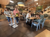 Menschen sitzen und stehen an Tischen in einem Cafe