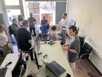 Eine Gruppe Menschen steht in einem Büro mit Computern und Bildschirmen 