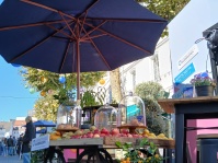 Holzwagen mit Obst und Gebäck unter Sonnenschirm