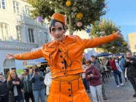 Straßenkünstlerin in orangefarbenem Kostüm
