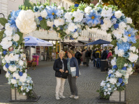 Zwei Frauen posieren unter Blumenbogen in der Innenstadt