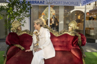 Frau auf rotem Sofa zwischen goldenen Figuren