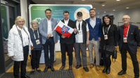 Gruppe von Menschen posiert gemeinsam vor Messewand
