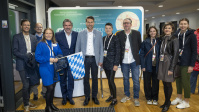 Gruppe von Menschen posiert gemeinsam vor Messewand