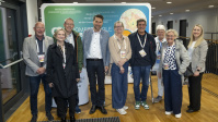 Gruppe von Menschen posiert gemeinsam vor Messewand