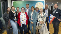 Gruppe von Menschen posiert gemeinsam vor Messewand