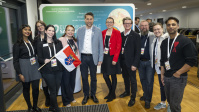 Gruppe von Menschen posiert gemeinsam vor Messewand