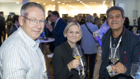 Drei Personen mit Weingläsern am Stehtisch beim Empfang