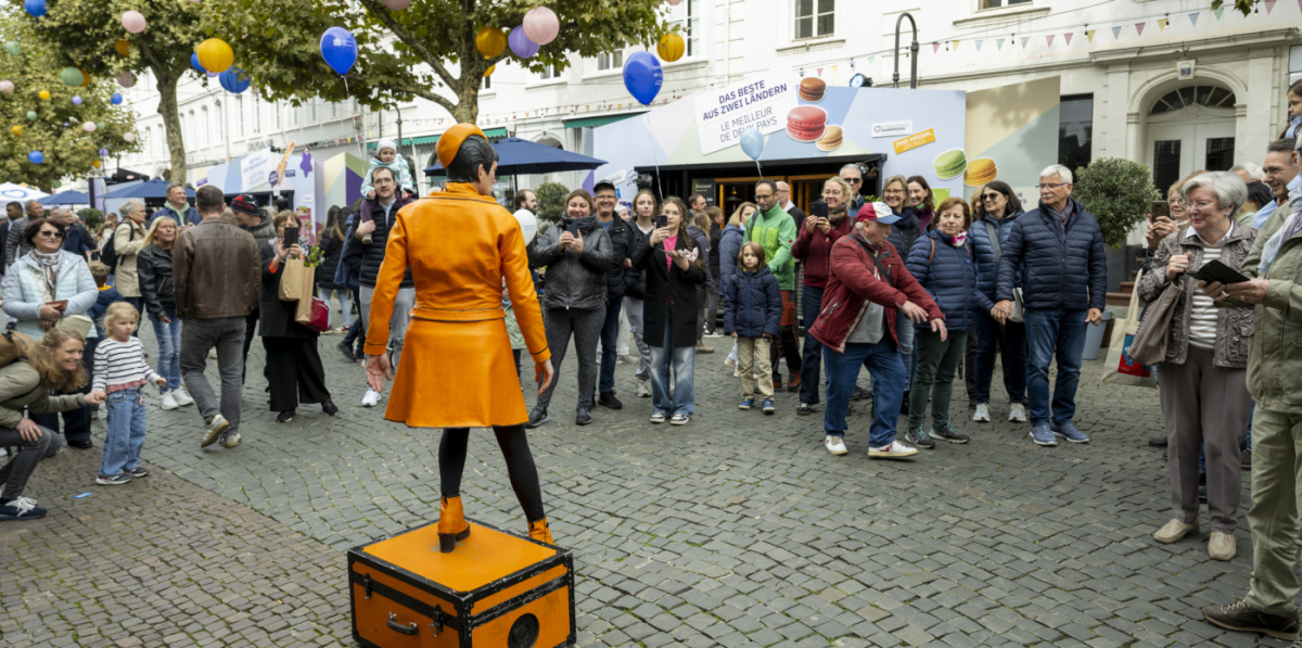 Festmeile der Landeshauptstadt beim Tag der Deutschen Einheit 2025 Publikum schaut Künstlerin in Orange auf Kiste an