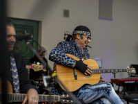 Musiker mit Gitarre trägt auffällige Kleidung