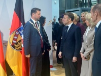 OB Uwe Conradt und der französische Präsident Emmanuel Macron stehen sich gegenüber, dahinter eine Saarland-Flagge