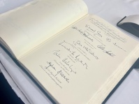 Ein Buch liegt aufgeschlagen auf einem Tisch, darin sind Eintrage und Unterschriften