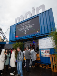 Containerbühne mit „moin“-Schriftzug des Hamburg-Stands beim Bürgerfest zum Tag der Deutschen Einheit in Saarbrücken, Besucher genießen Programm und Getränke.